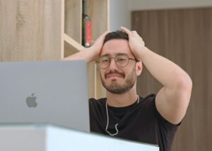 person looking at laptop with hands on their head