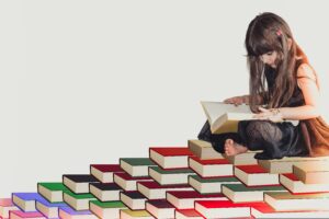 young girl reading while sitting on a pile of books