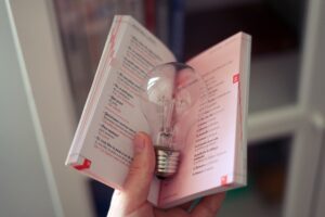 person holding a book with a light bulb in the book, to represent an idea from the reading