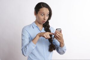 woman reacting with surprise to something seen on her phone