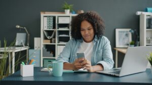 woman at desk with laptop and phone