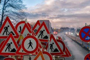 multiple road signs that show road work ahead, crossing ahead, and more