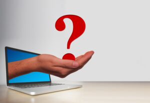 hand coming out of a laptop screen and holding a question mark