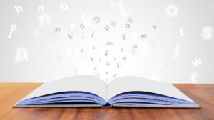open textbook with letters flying off of the pages