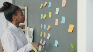 woman contemplating sticky notes arranged on a wall