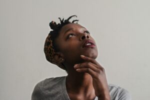 person looking upward, hand on their chin, deep in thought