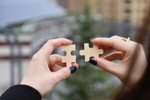 person holding two pieces of a puzzle to put together