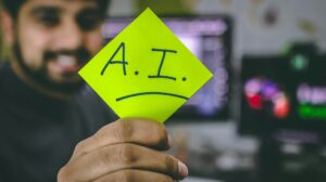 student holding up a sticky note that says AI